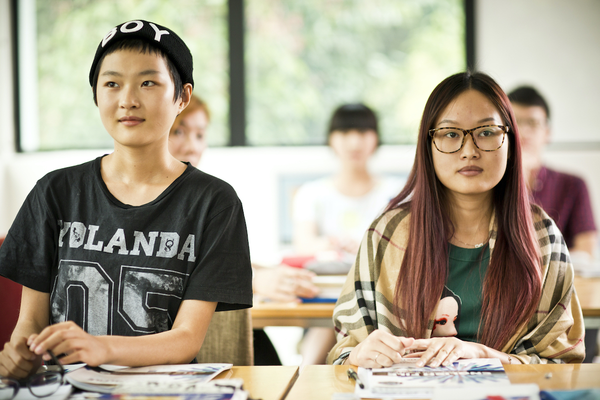 Two female teenage students smiling and sitting at a table