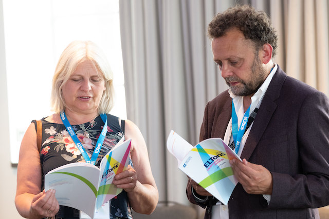 Two people looking at the ELTons awards programme booklet