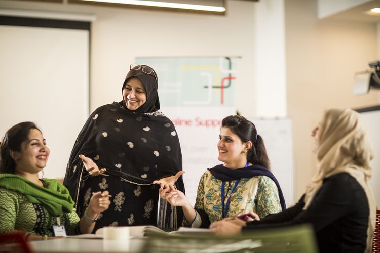 A group of Asian women teachers talking together in a teachers' room