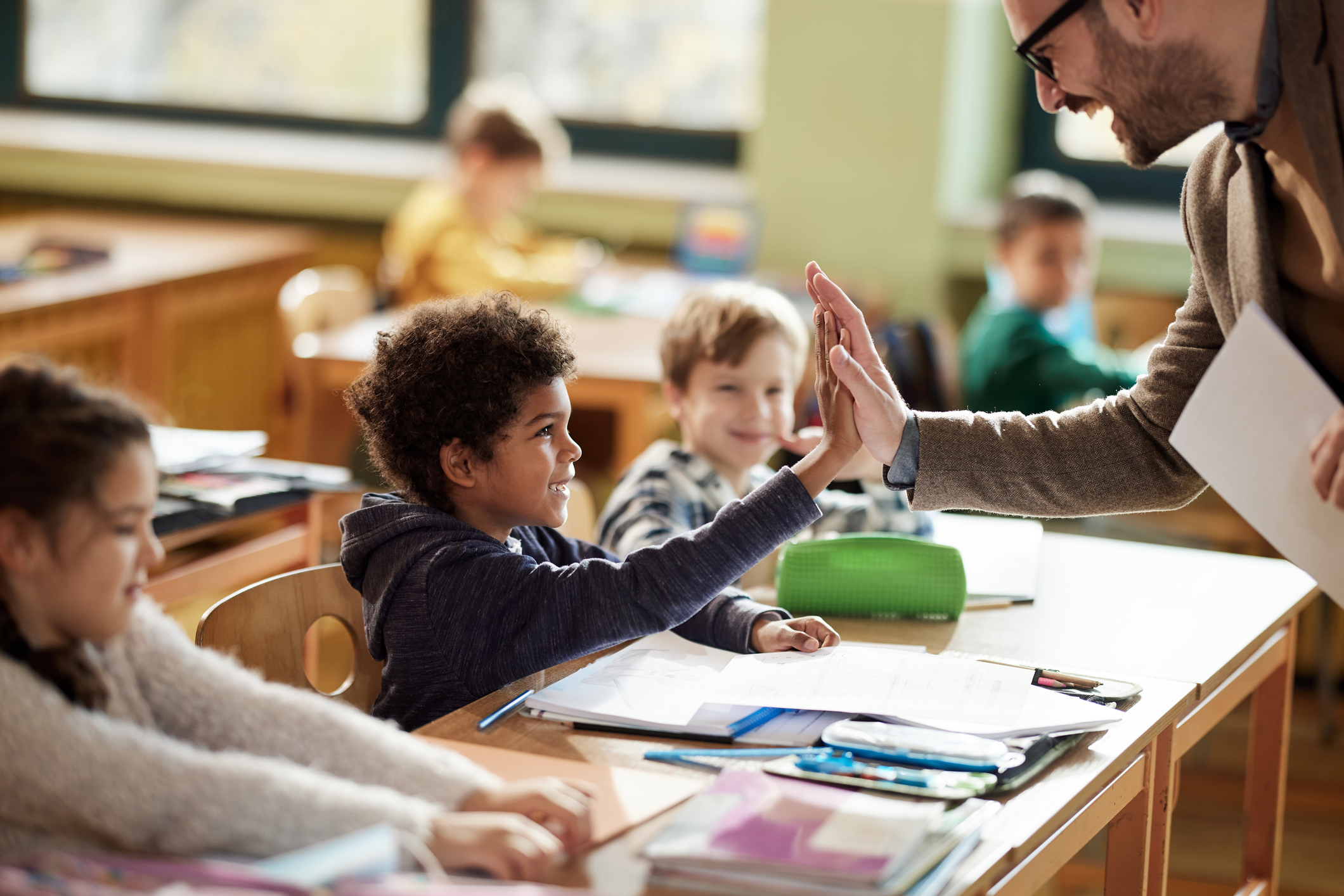 Teacher gives a high-five to a young learner in a classroom