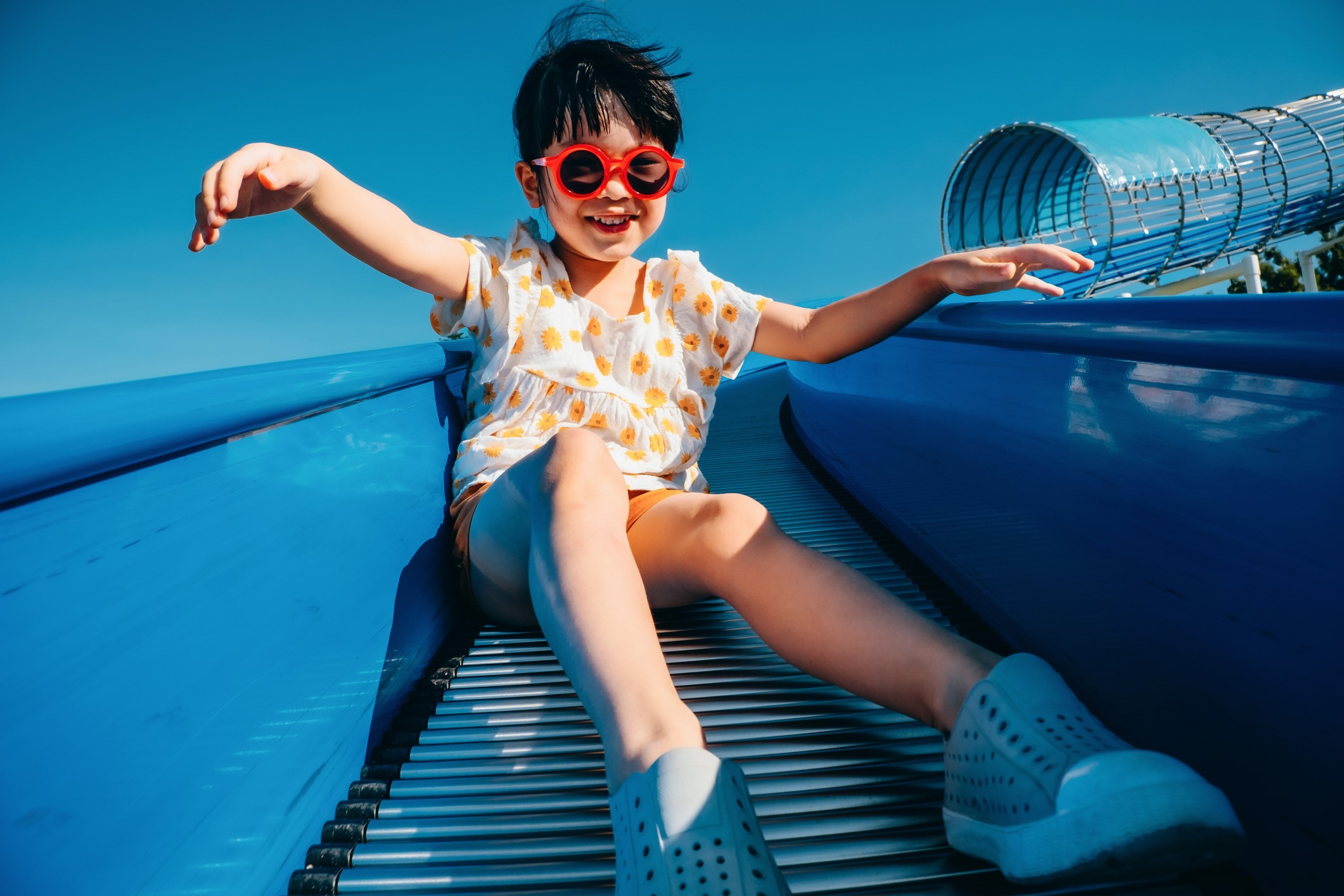 Asian girl playing joyfully on a slide