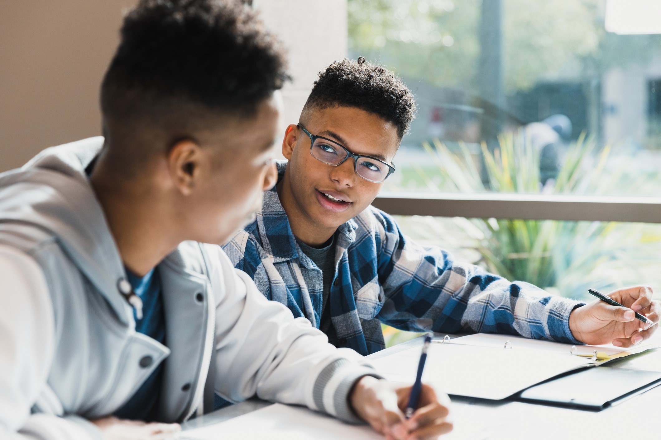 Two Black teenage boys talking and thinking together in class