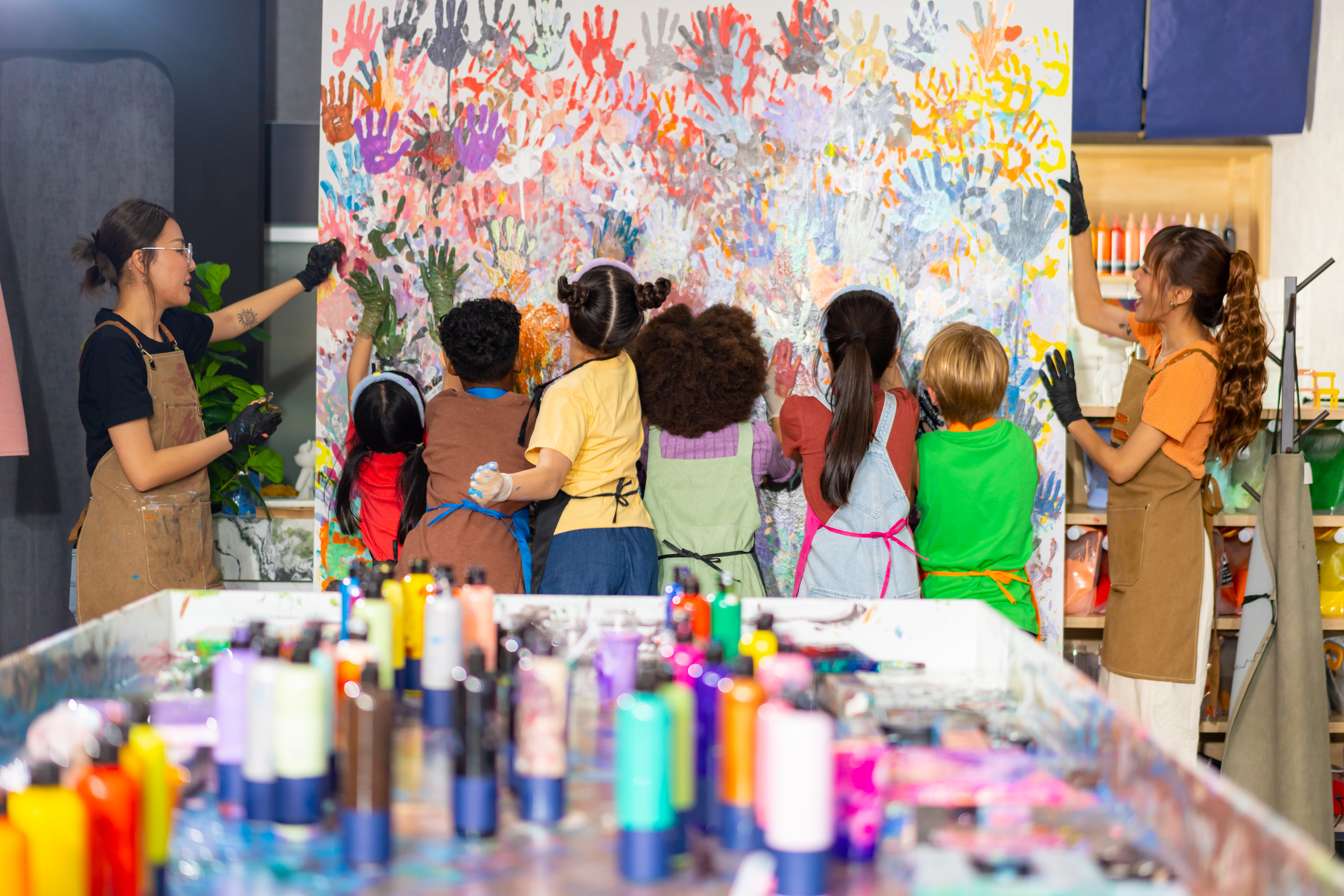 Group of ethnically diverse young learners doing a huge hand painting in a classroom