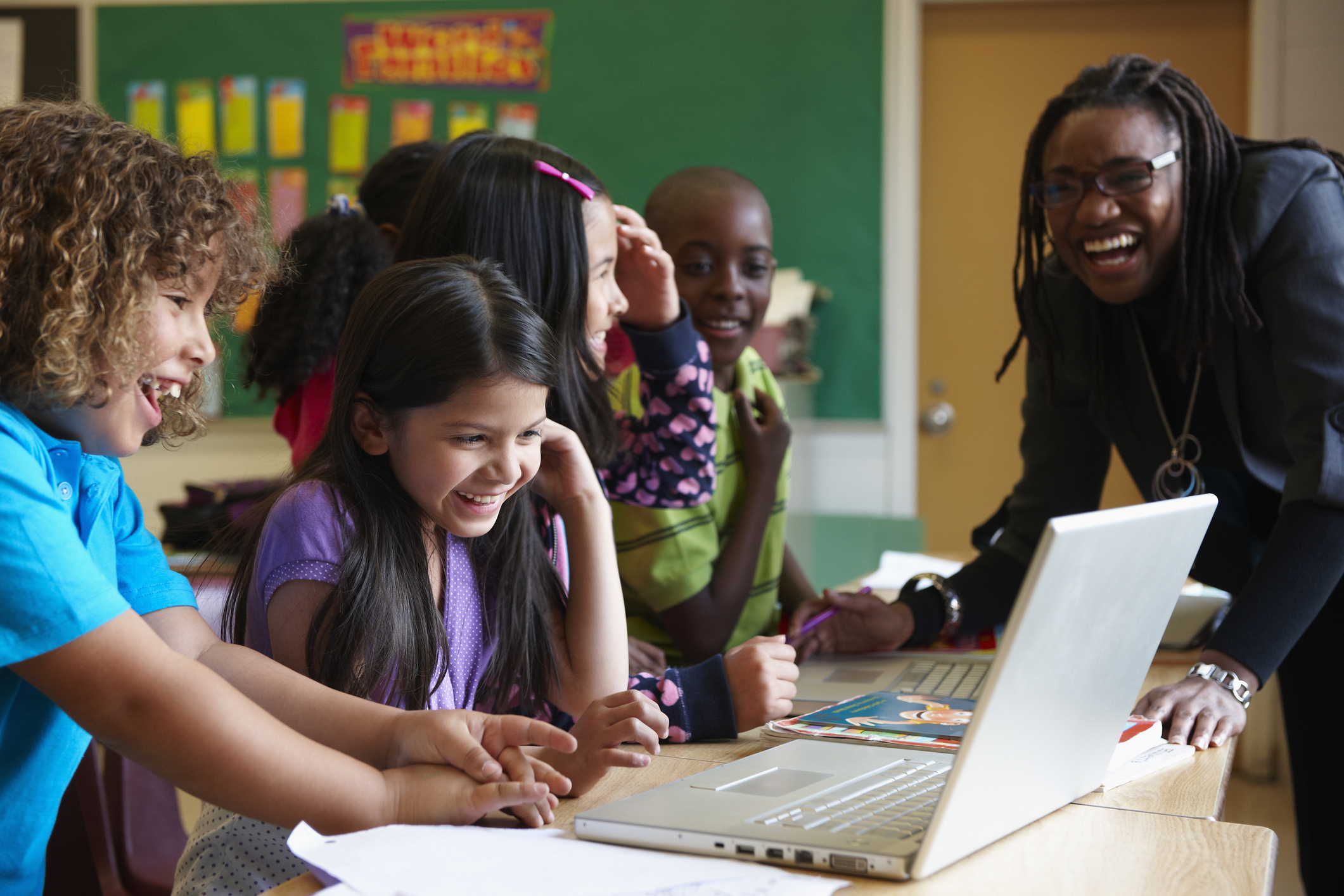 Diverse primary students enjoying working together on laptops