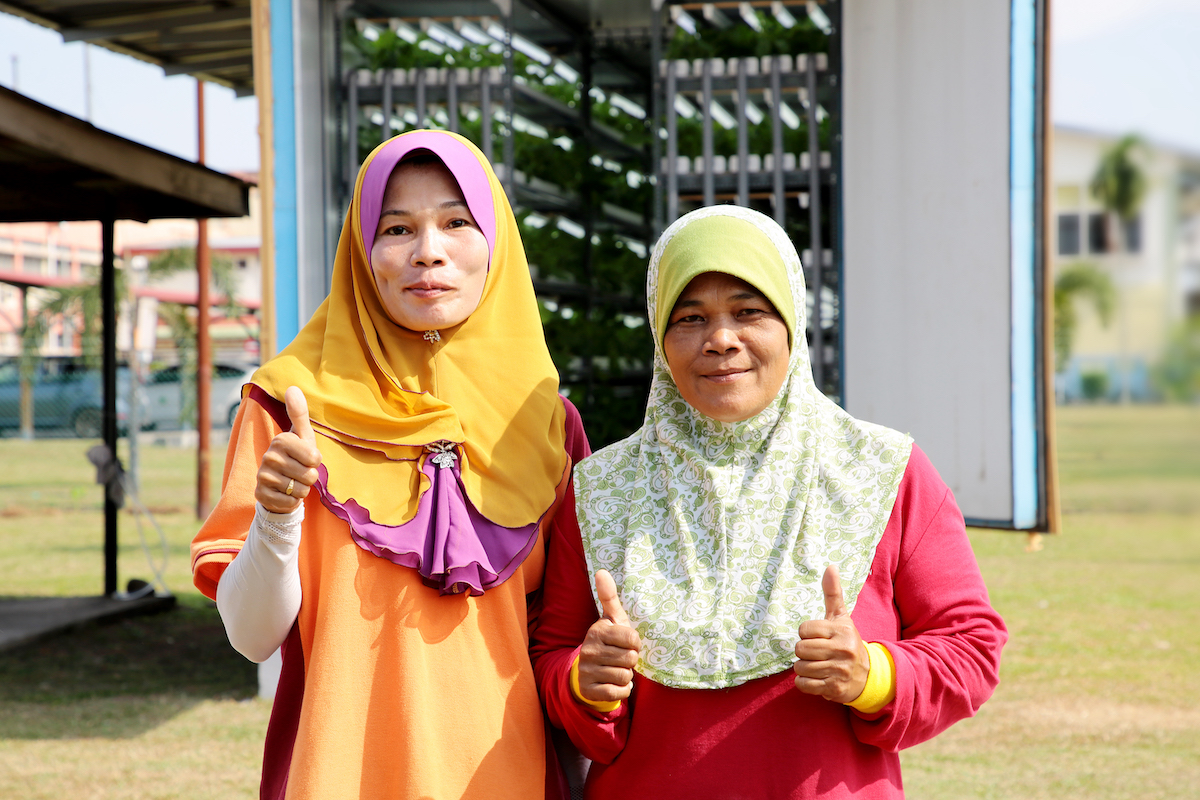 Two women with colourful clothes giving the thumbs up gesture