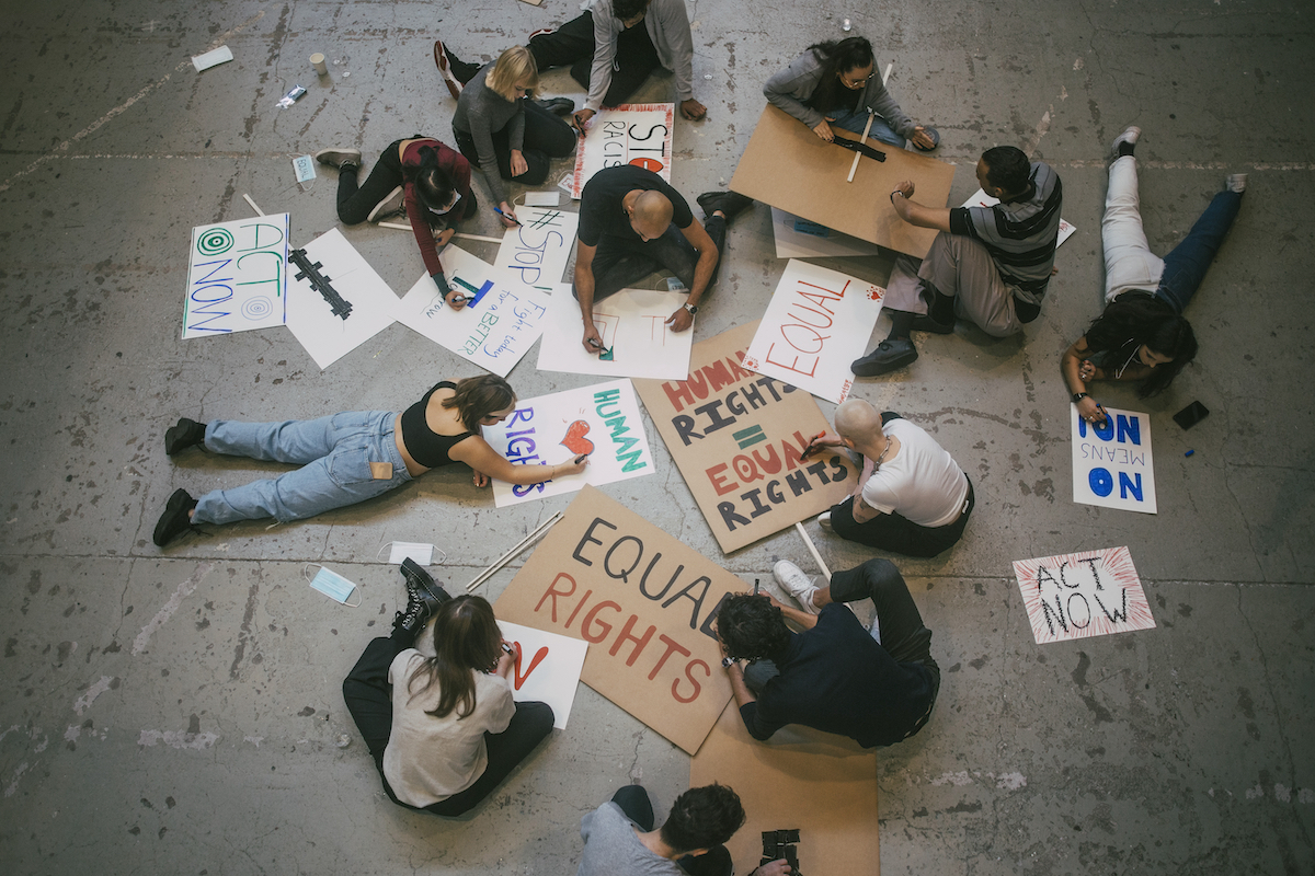 students and teacher making posters on the floor