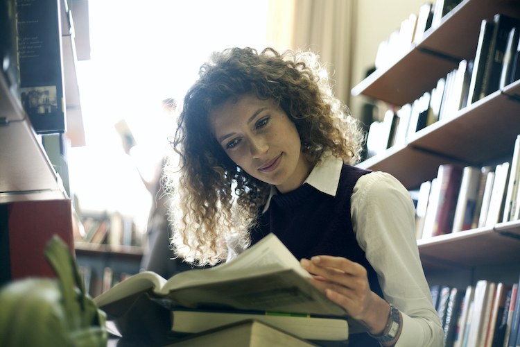 Woman in library sitting down looking at a book