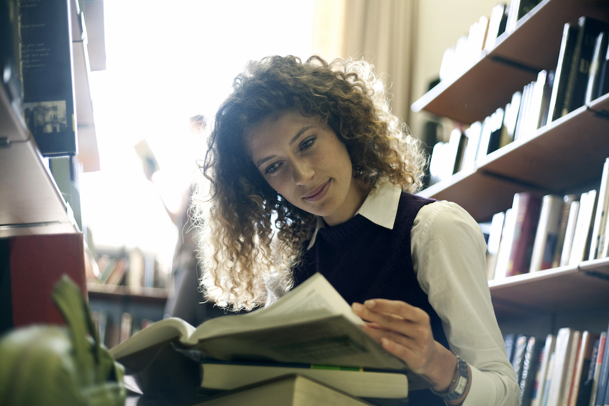 Female teacher looking through a book in a library