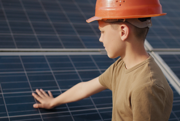 A child in a helmet is touching some solar panels