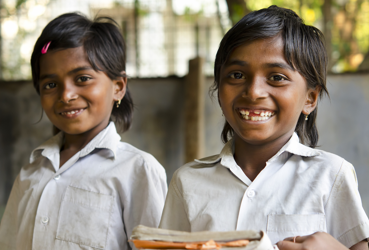 two smiling school children with note books