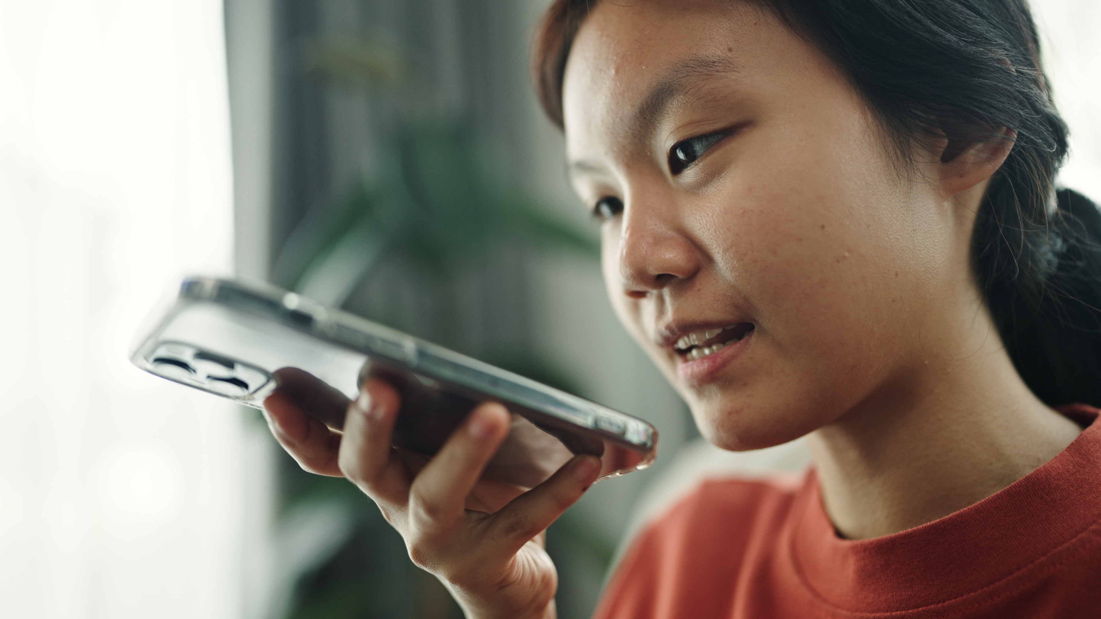 Young Asian student speaking to a chatbot on her smartphone