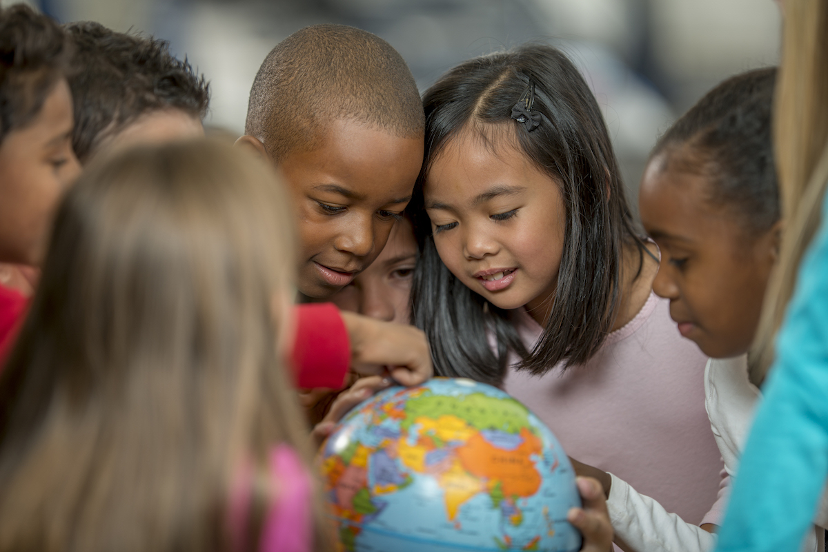 Children pointing out places on a globe