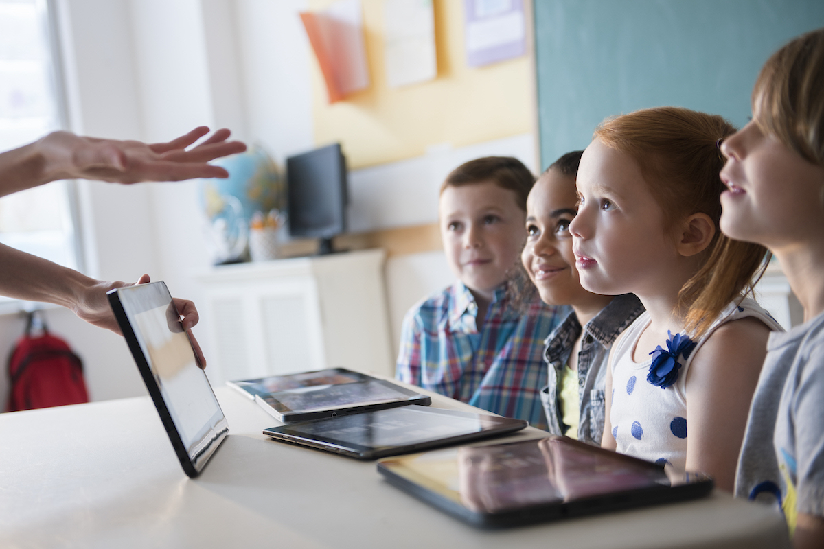 children in class, teacher encouraging them to participate