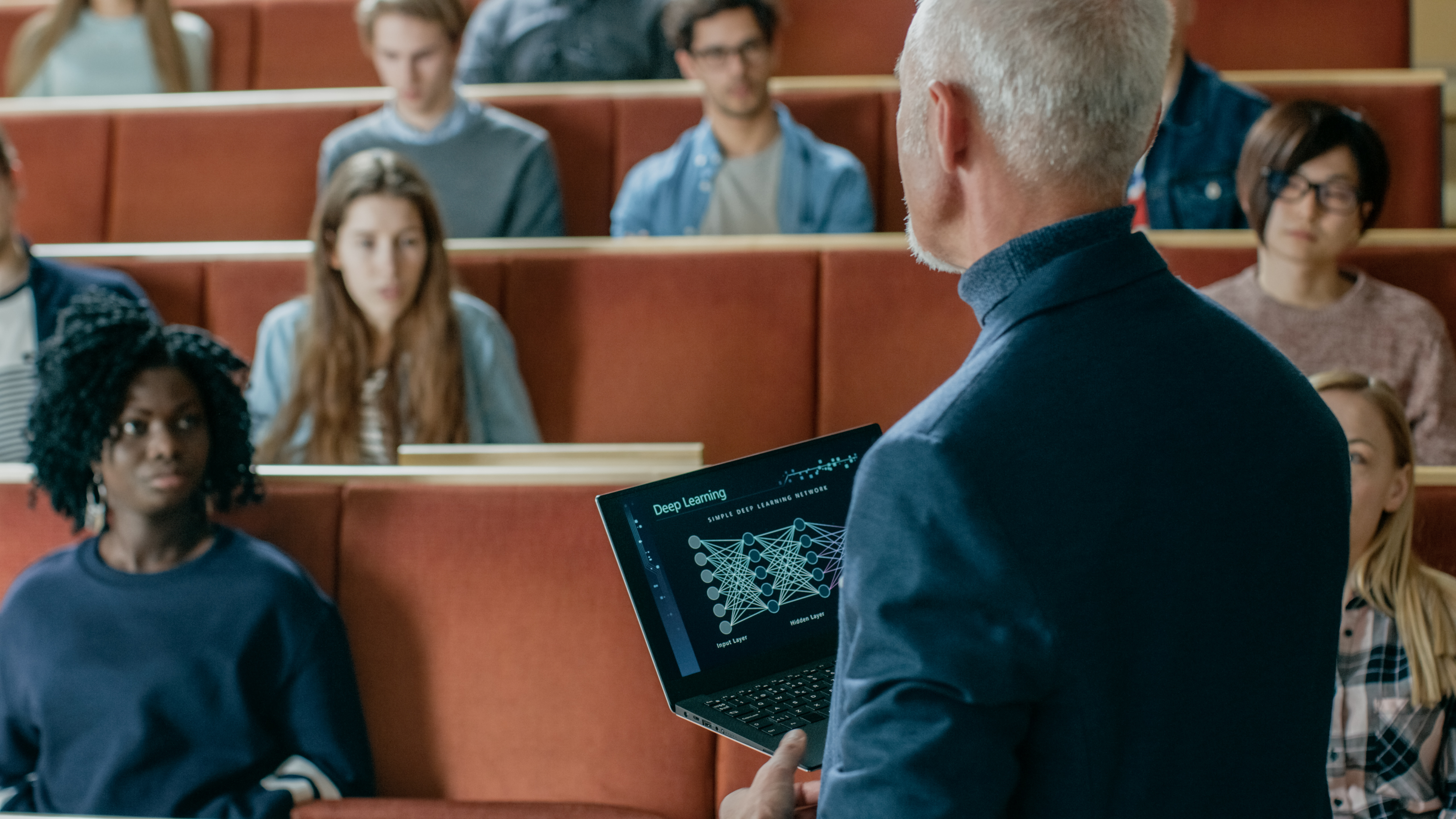 a professor talking to his students whilst using a chatbot on his laptop