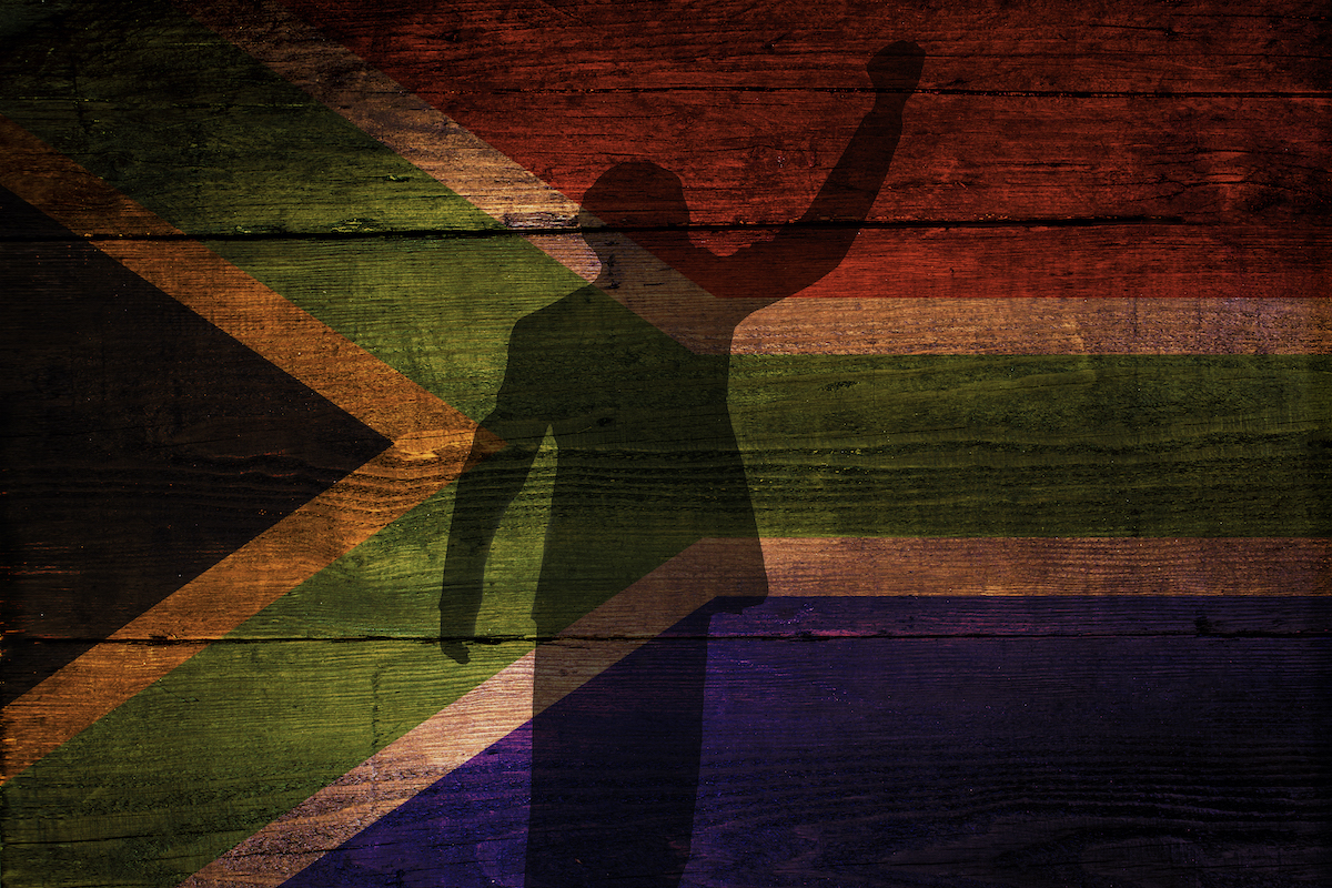 A silhouette of Mandela in front of South African flag