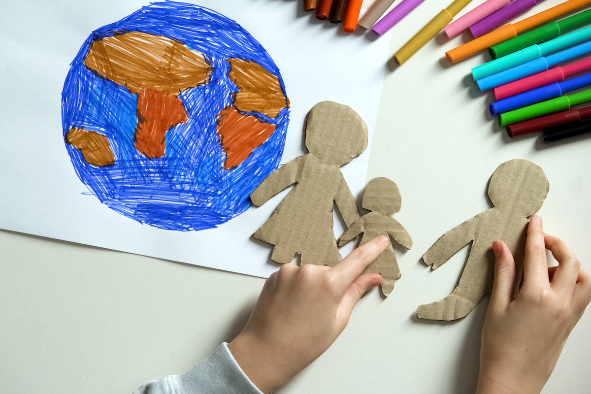 Child putting paper family near Earth drawing