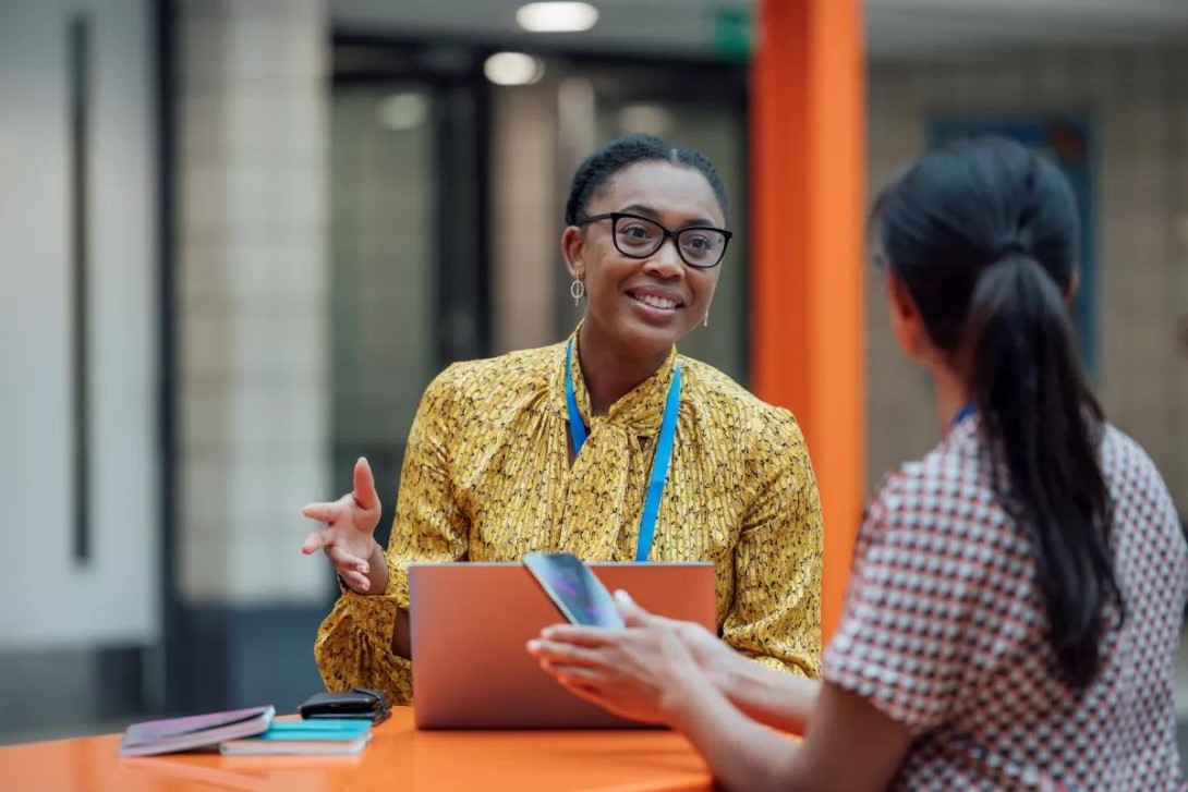 Smartly dressed Black teacher talking to her colleague