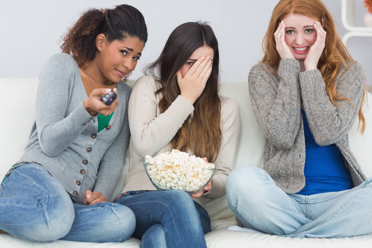 Three young women with popcorn watching TV