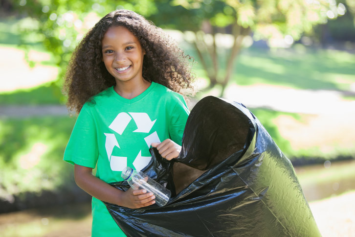 A girl putting a plastic bottle in a recycling bag