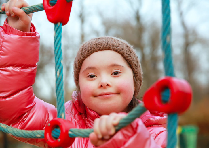 A young girl with Down's Syndrome at a playground