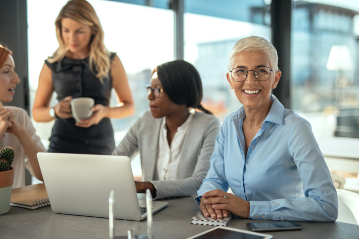 Four women talking in front of a laptop computer