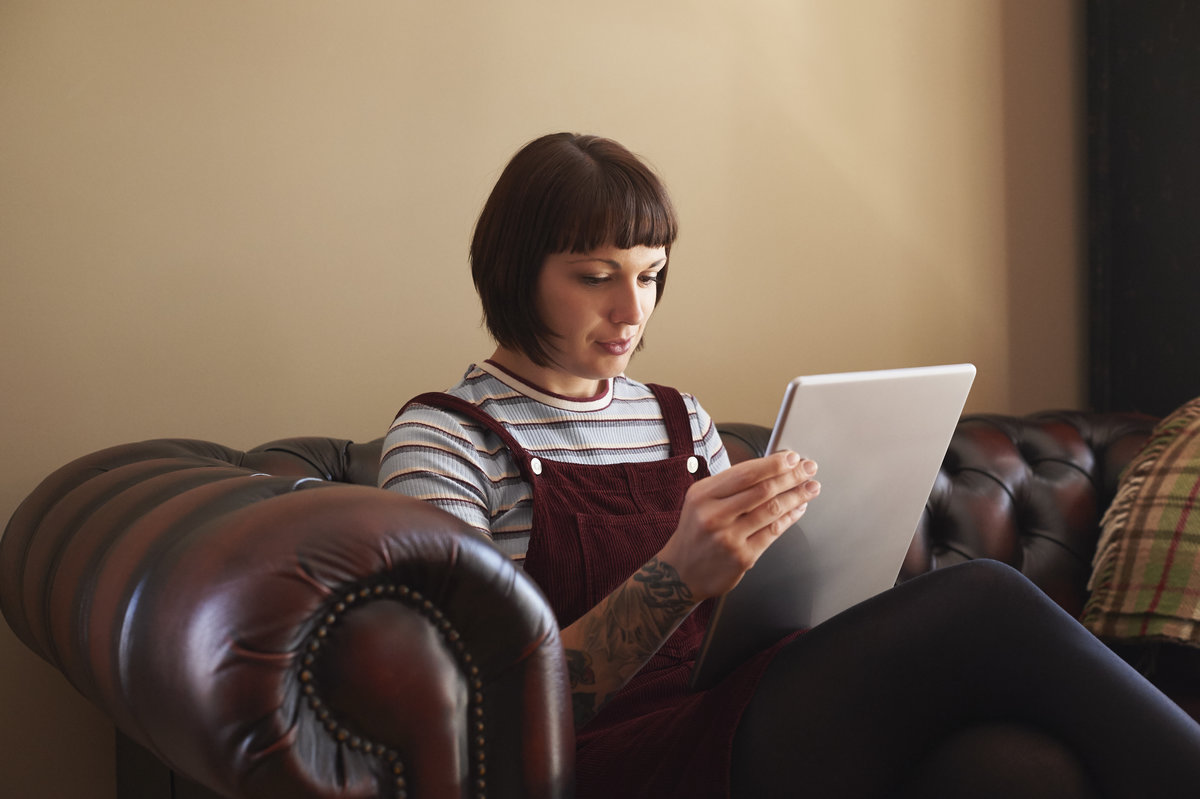 A woman with a tattoo on her arm is sitting on a sofa