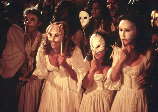 A scene from a film - young women wearing masks at a party