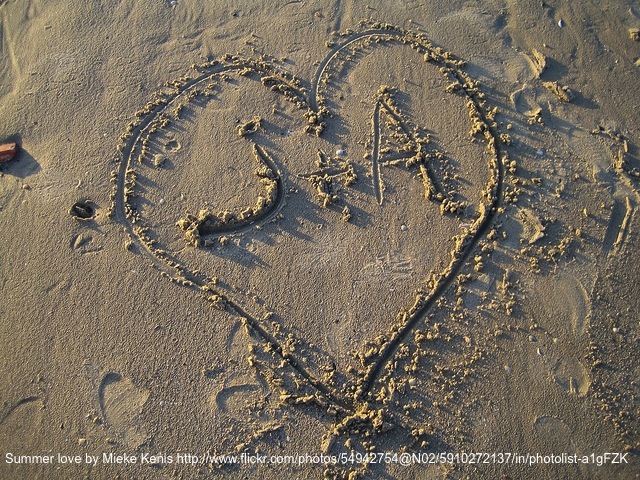 A heart drawn in the sand with two initials in the middle