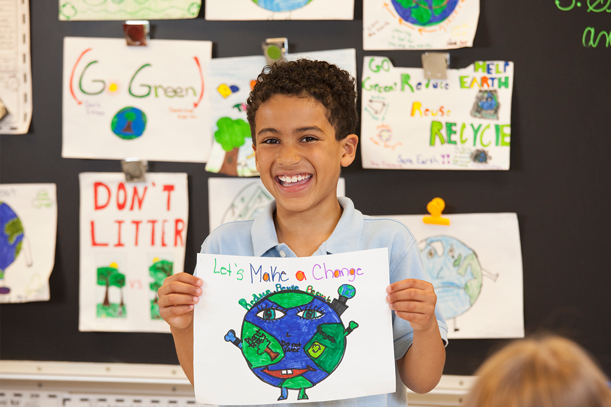 A learner holding his climate action poster titled Lets Make A Change