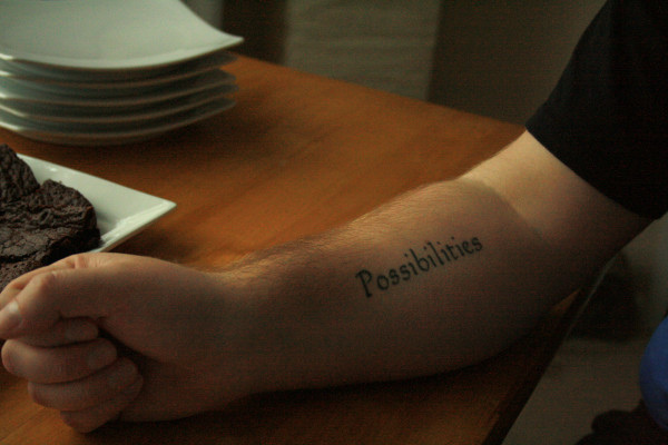 A man's arm with a tattoo saying 'possibilities'