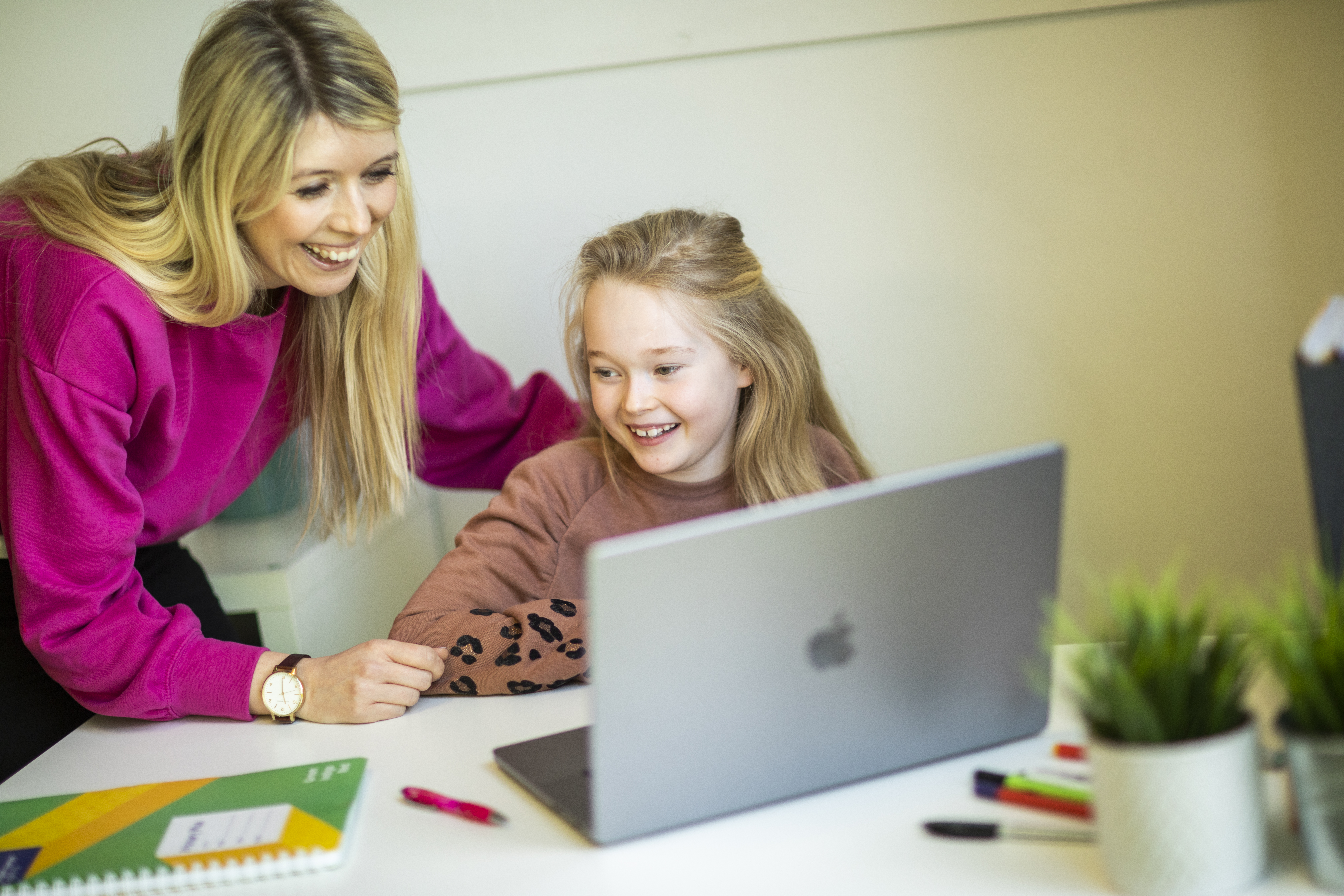 A young learner learning online with a woman next to her