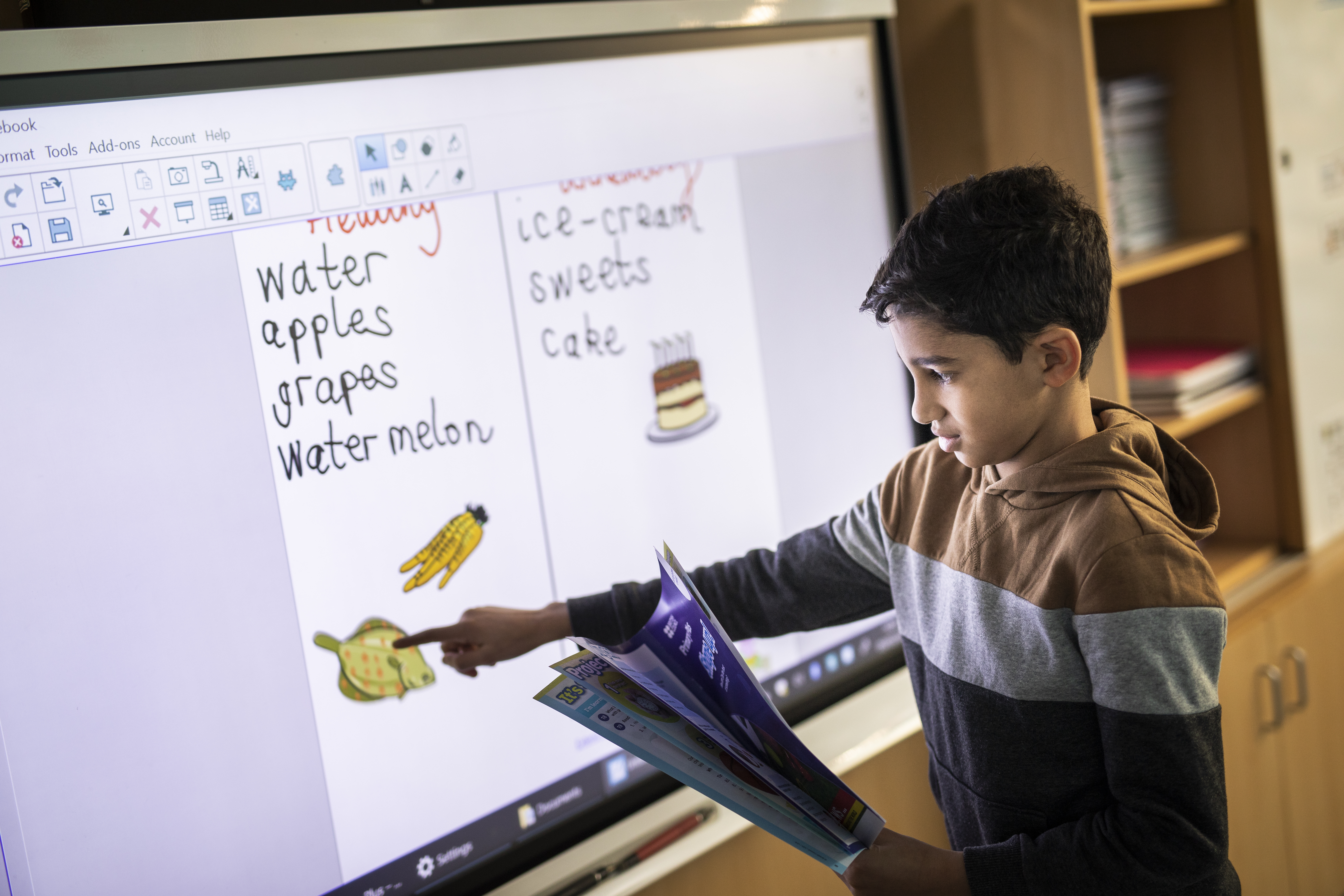 A young learner moving an image on an IWB