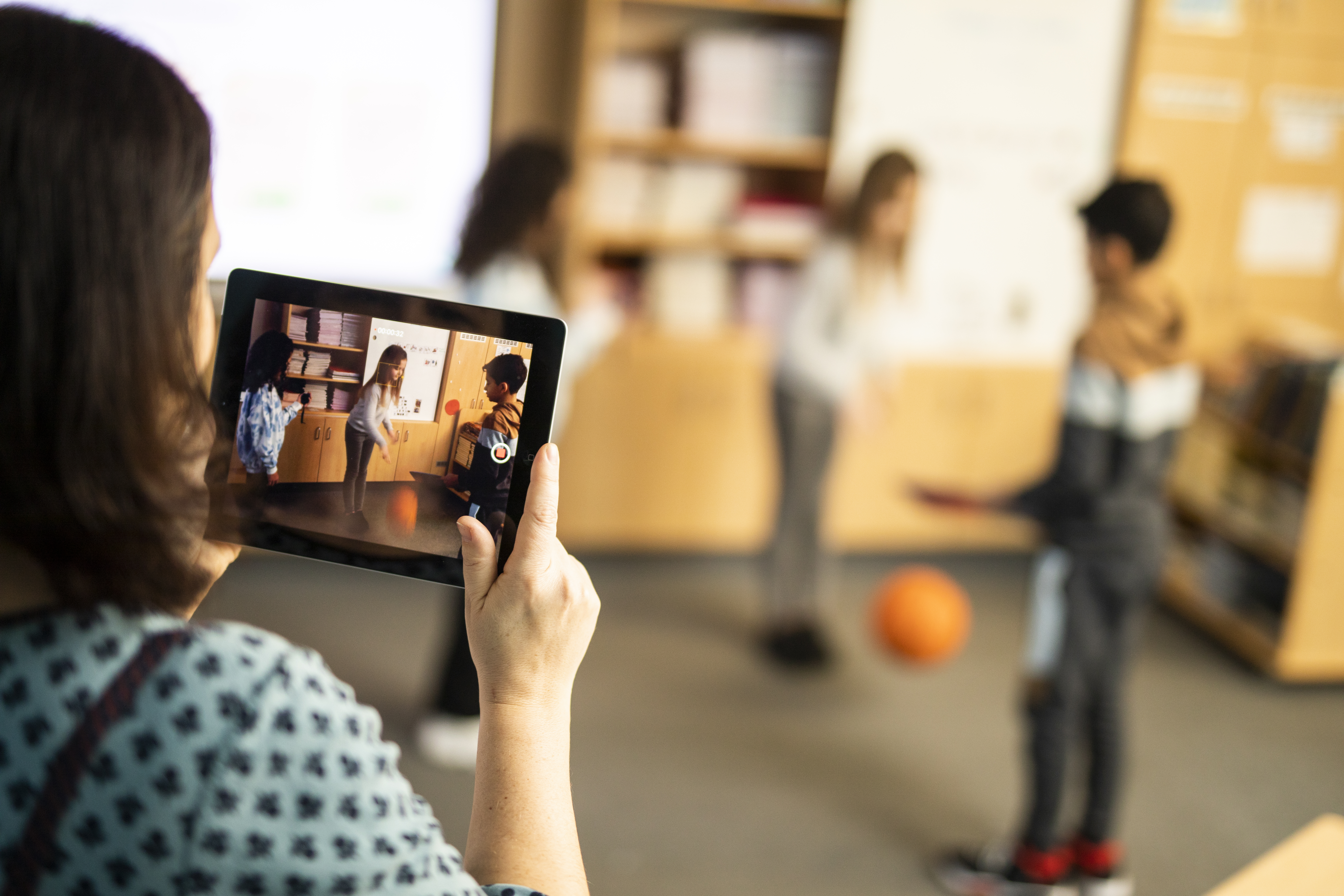 A teacher filming some young learners playing in a classroom