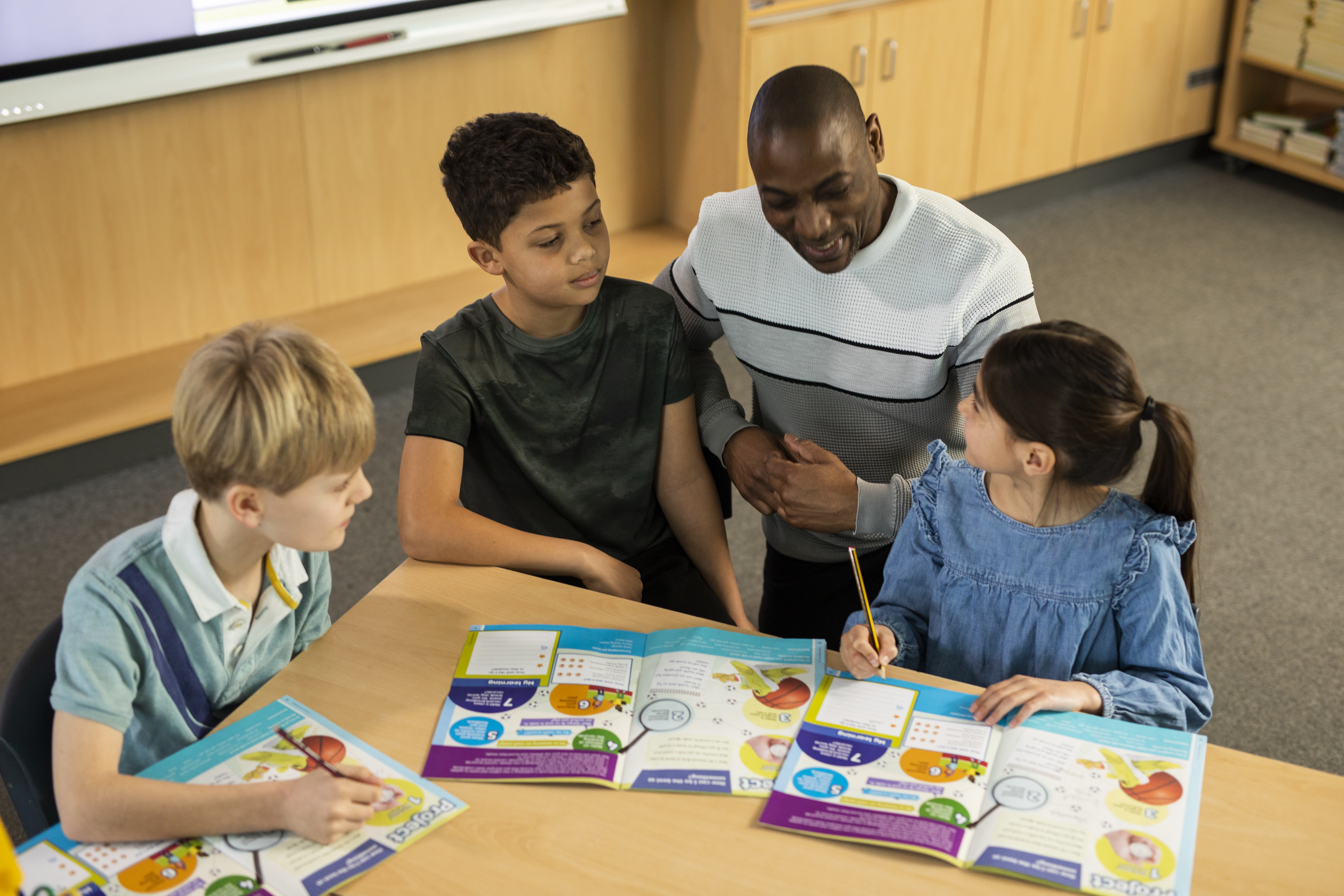 Young learners with a teacher looking at magazines