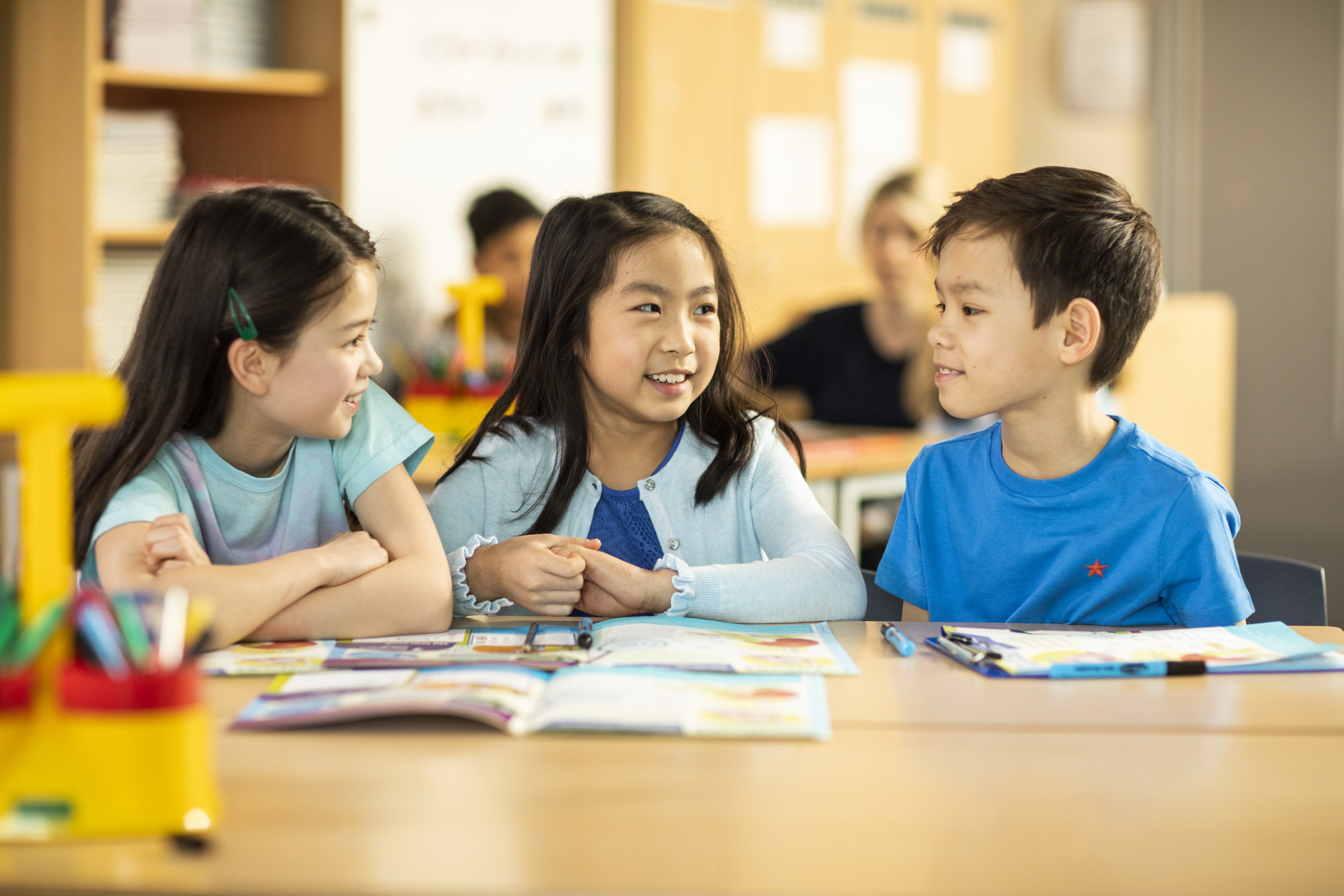 three young learners talking in a classroom