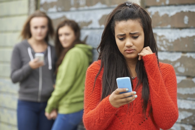 girl looking at mobile phone while other girls watch her