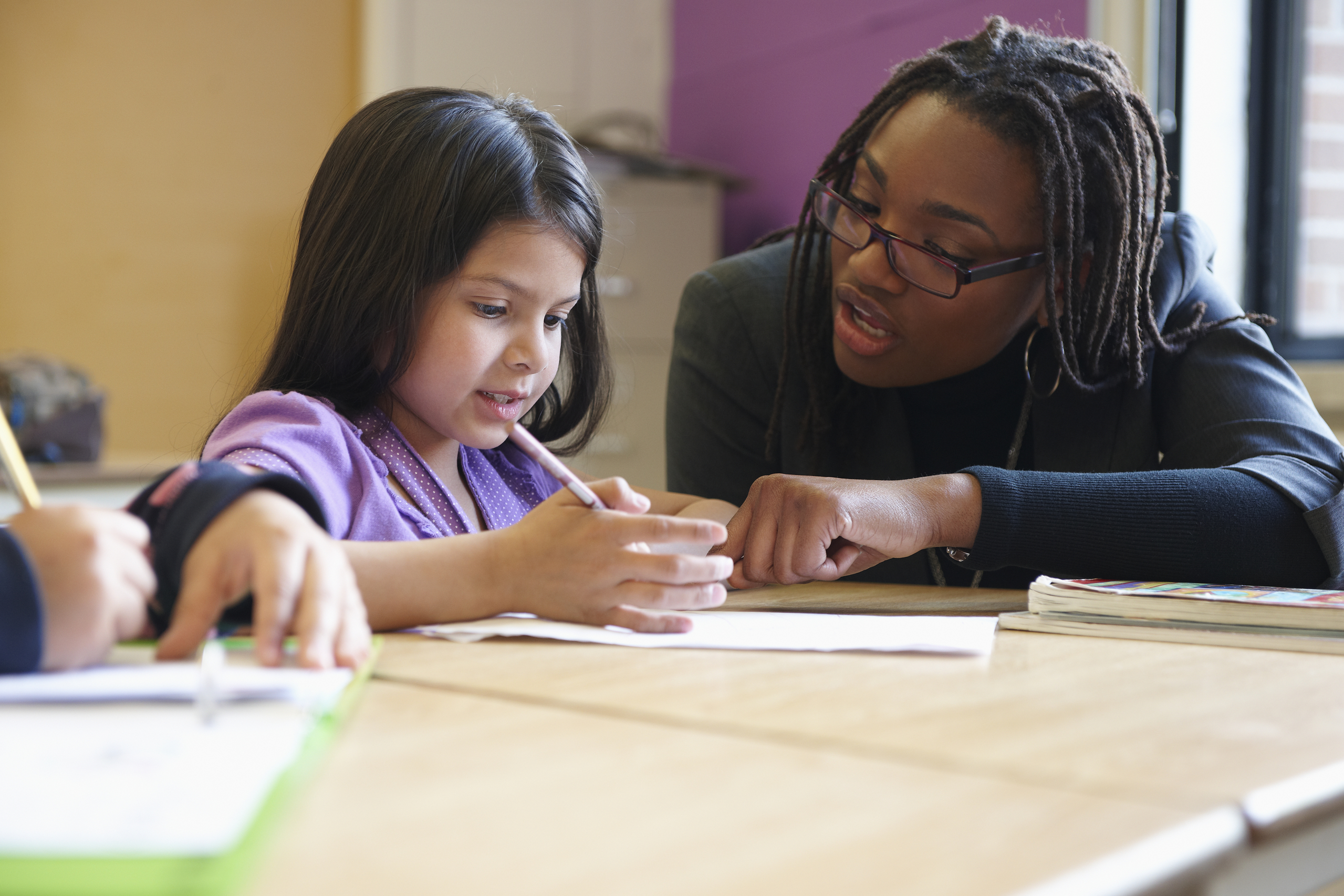 Teacher helping a learner with reading in classroom