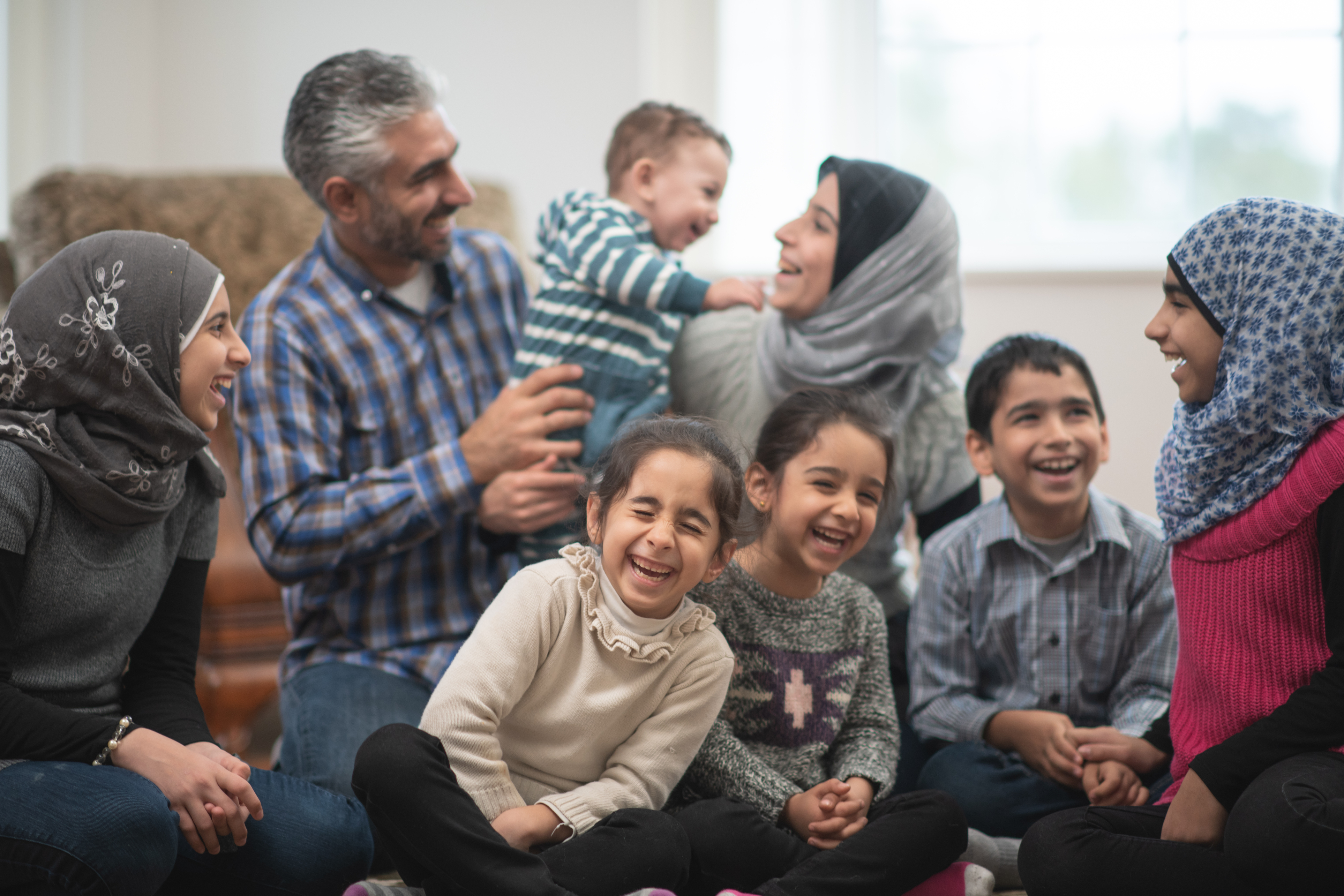 Large Muslim family laughing together at home