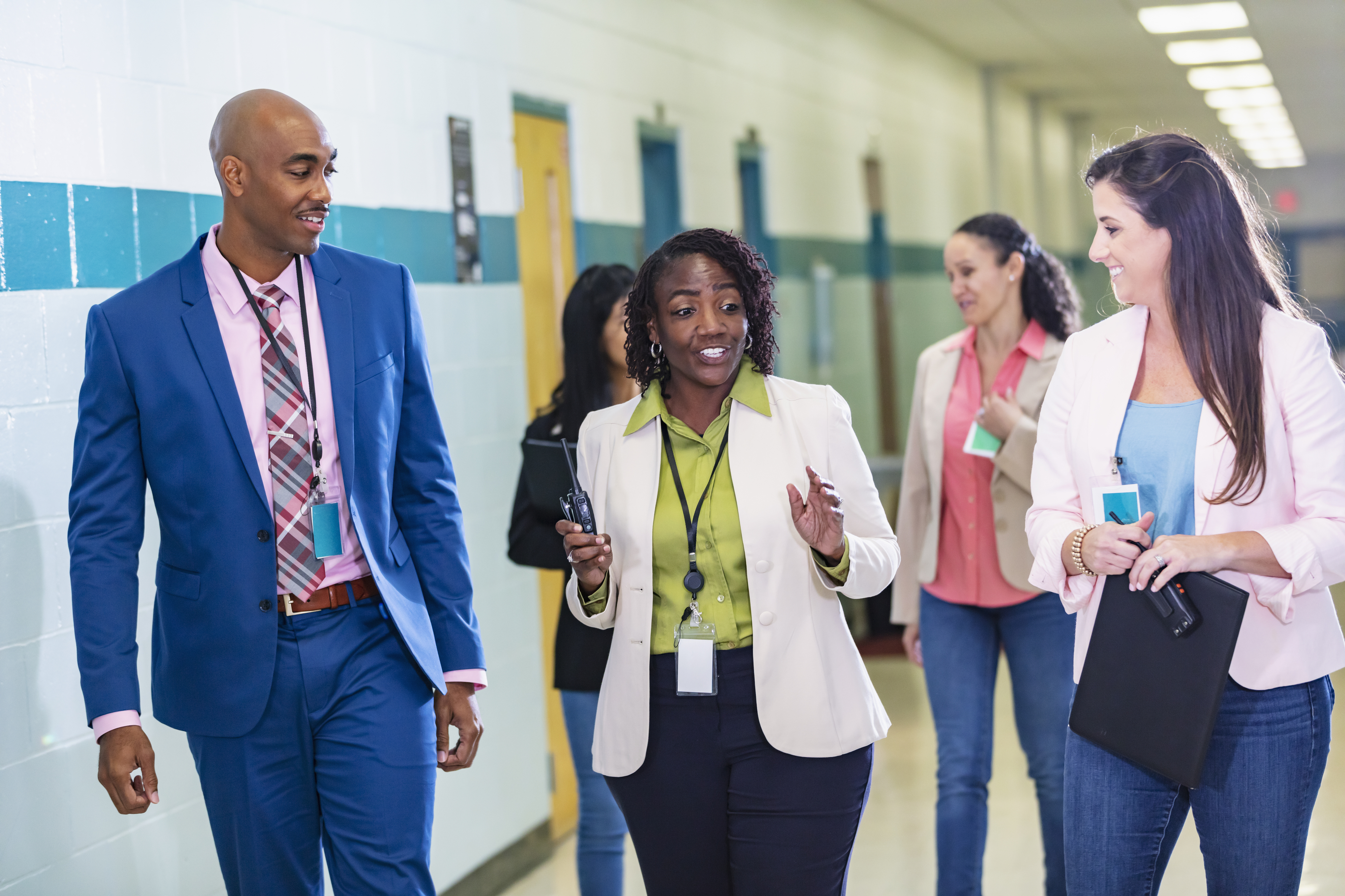 Group of diverse teachers talking together in a school corridor