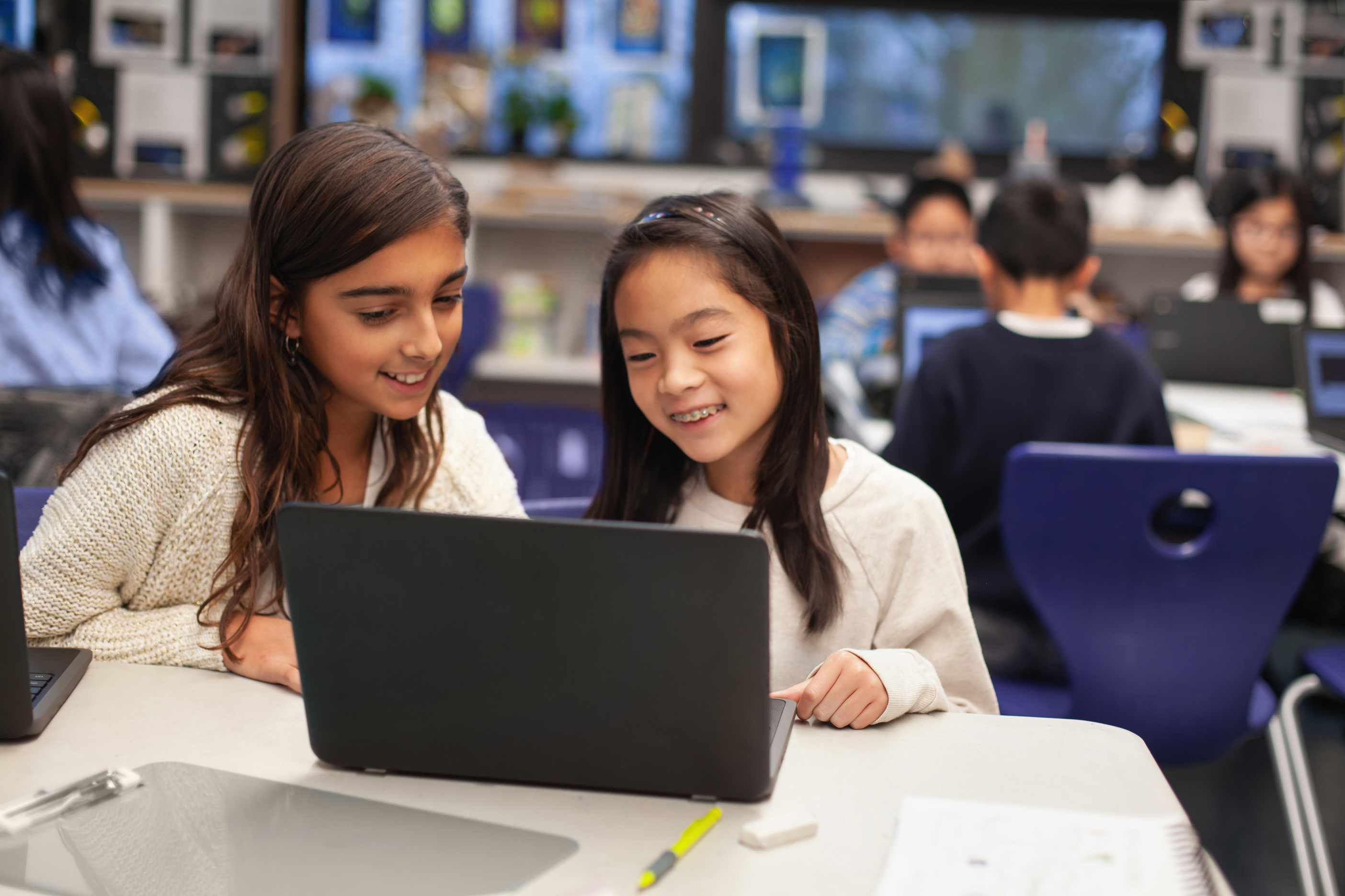 Two Asian young learners look at a screen in class