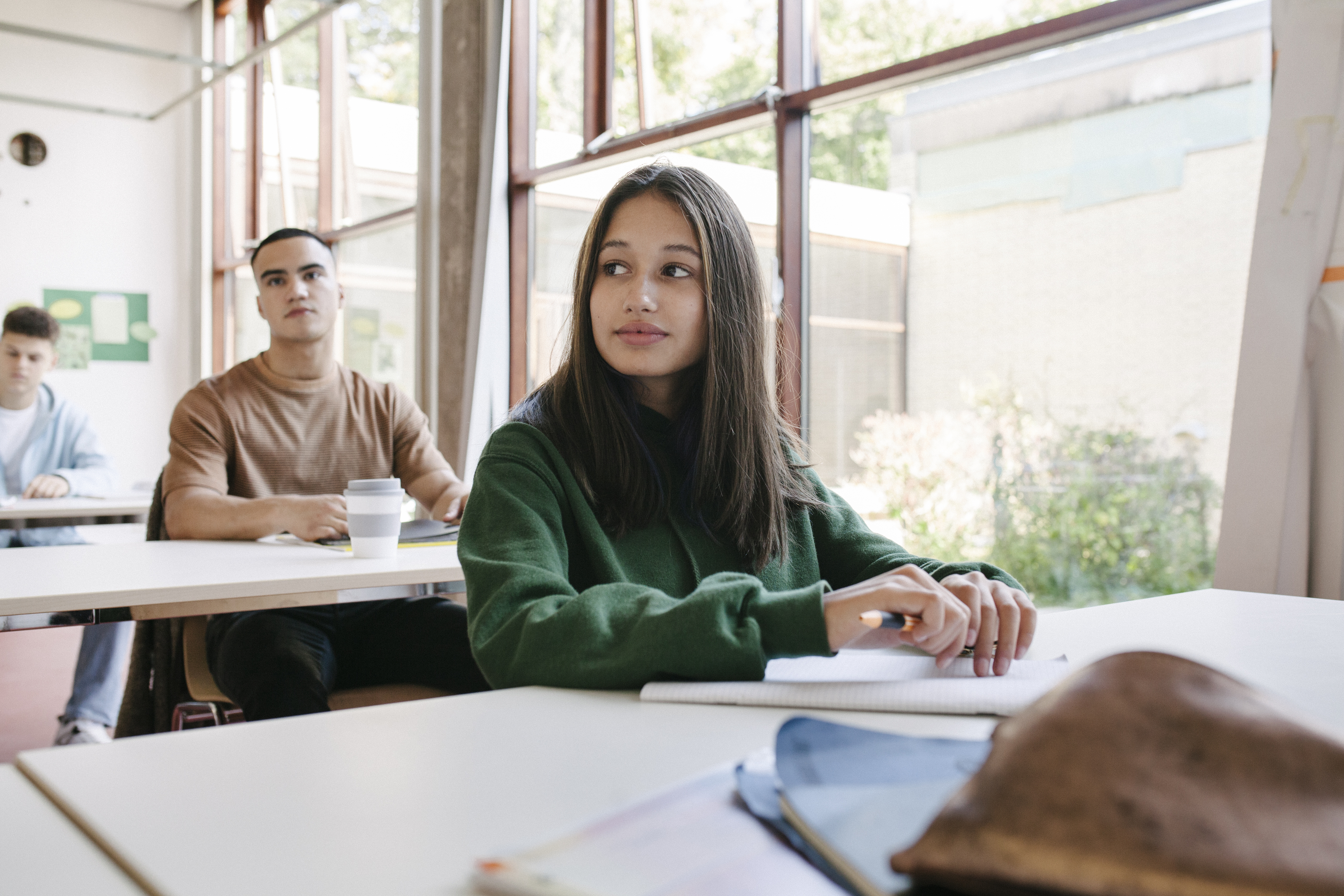 Teenage girl sitting at school desk staring off to her right