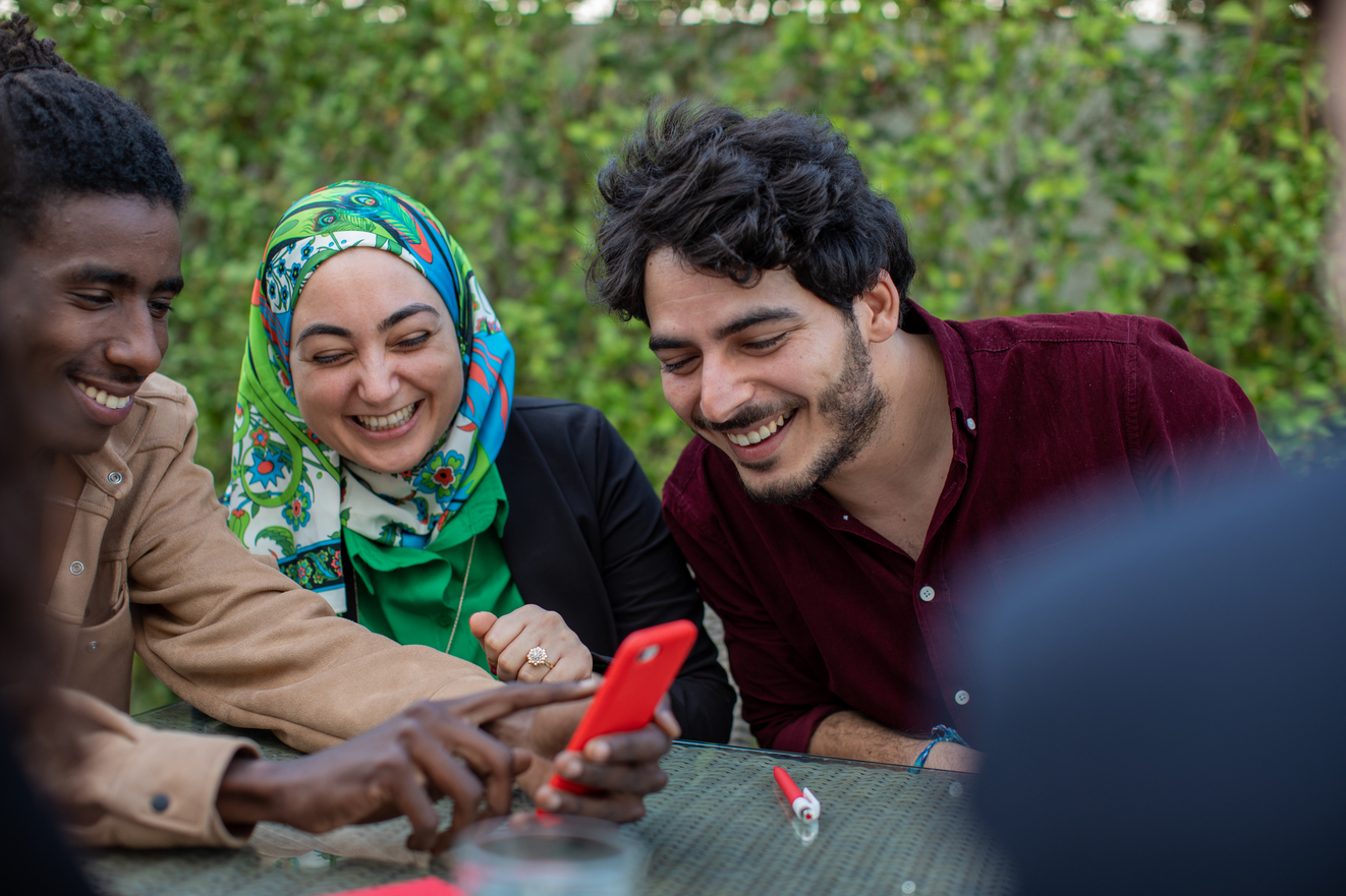 Three Tunisian friends laughing about a text message