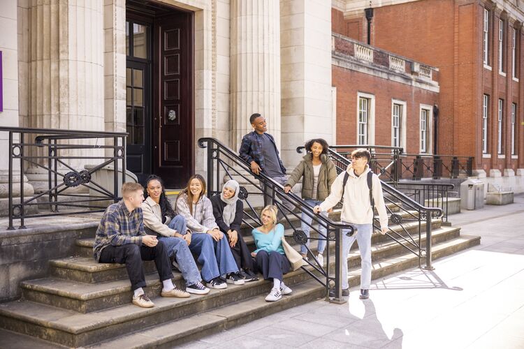 Adult students in the UK, sitting on stairs talking