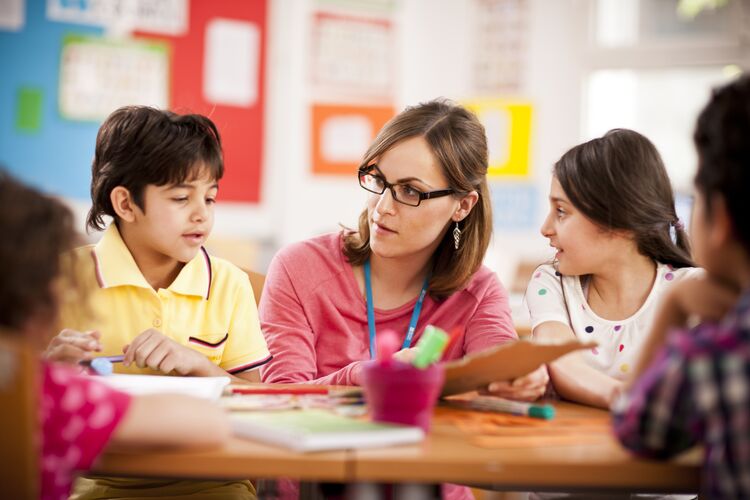 Teacher in Bahrain sitting next to students talking to them