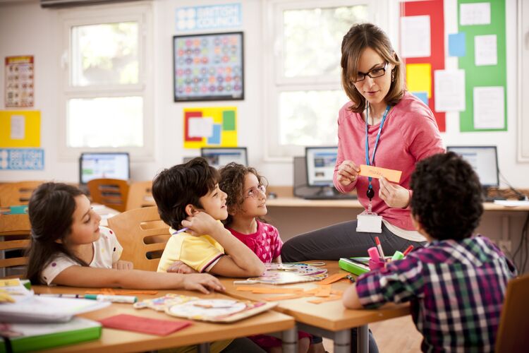 A teacher sitting on a table with a group of students in Bahrain