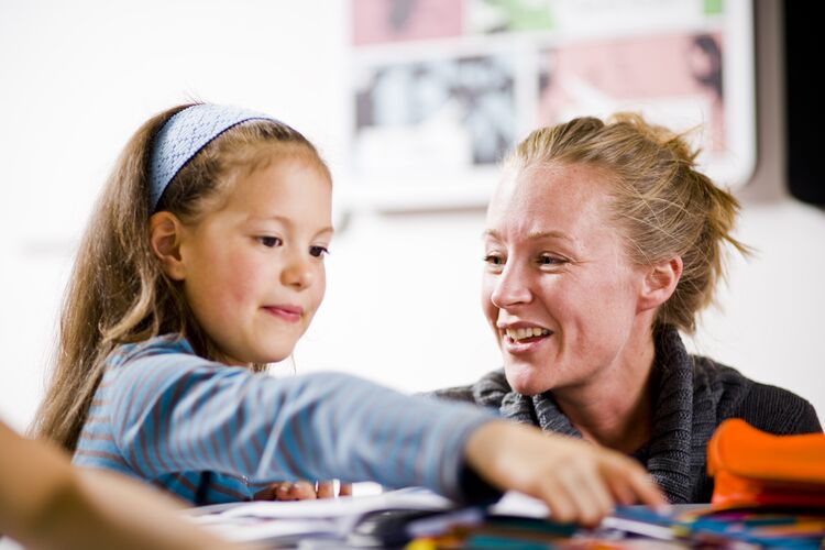 A teacher sitting with a young learner in classroom in Colombia