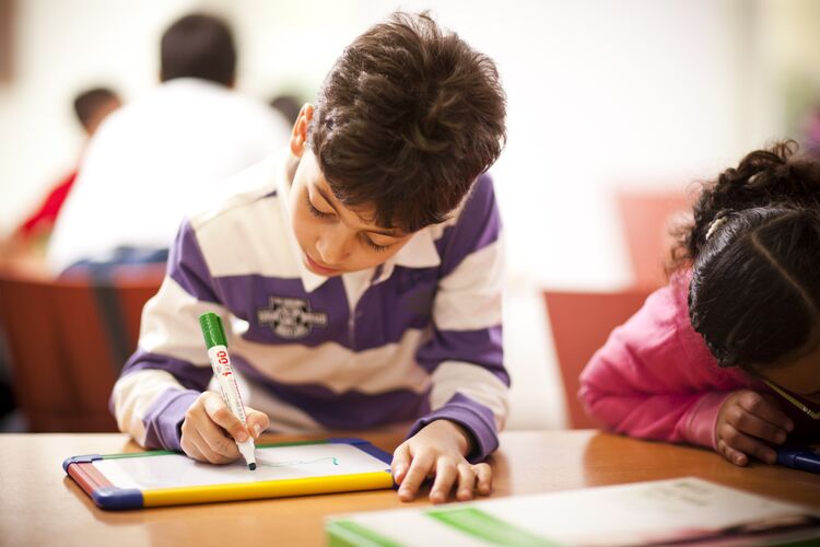 Boy writing on a mini whiteboard in the classroom