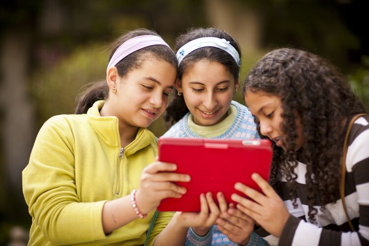 Three young learners in Egypt looking at a tablet