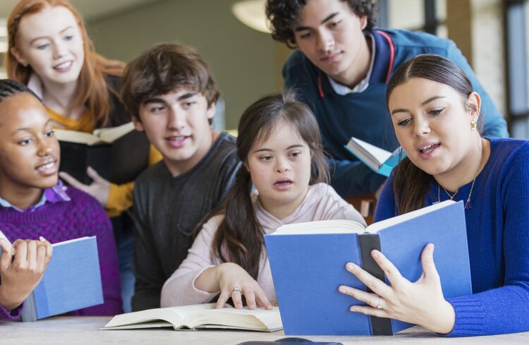 Teenage learner with Down's syndrome reading in class with friends