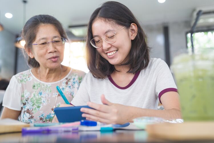 Asian teenager with her grandmother reading on a tablet